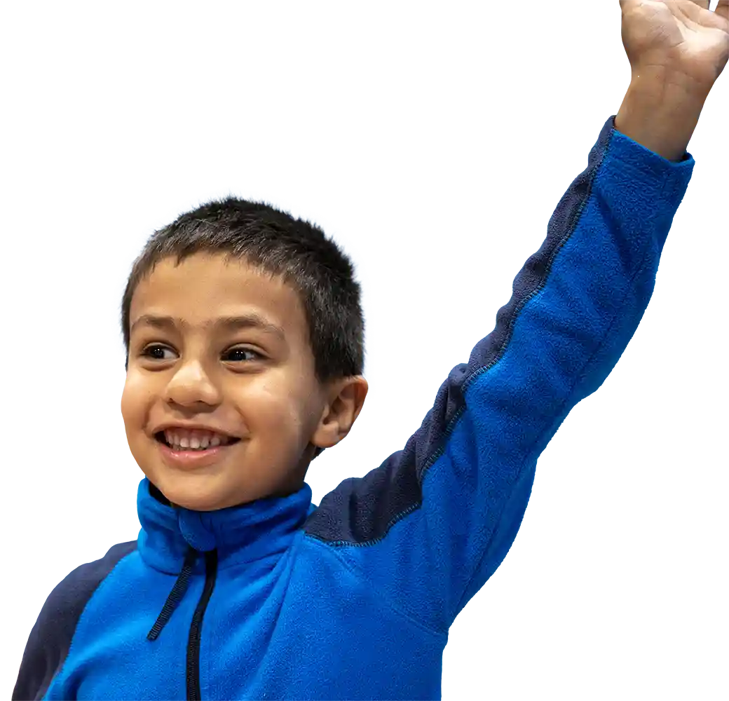 Young boy in tracksuit top, smiling with one hand in the air